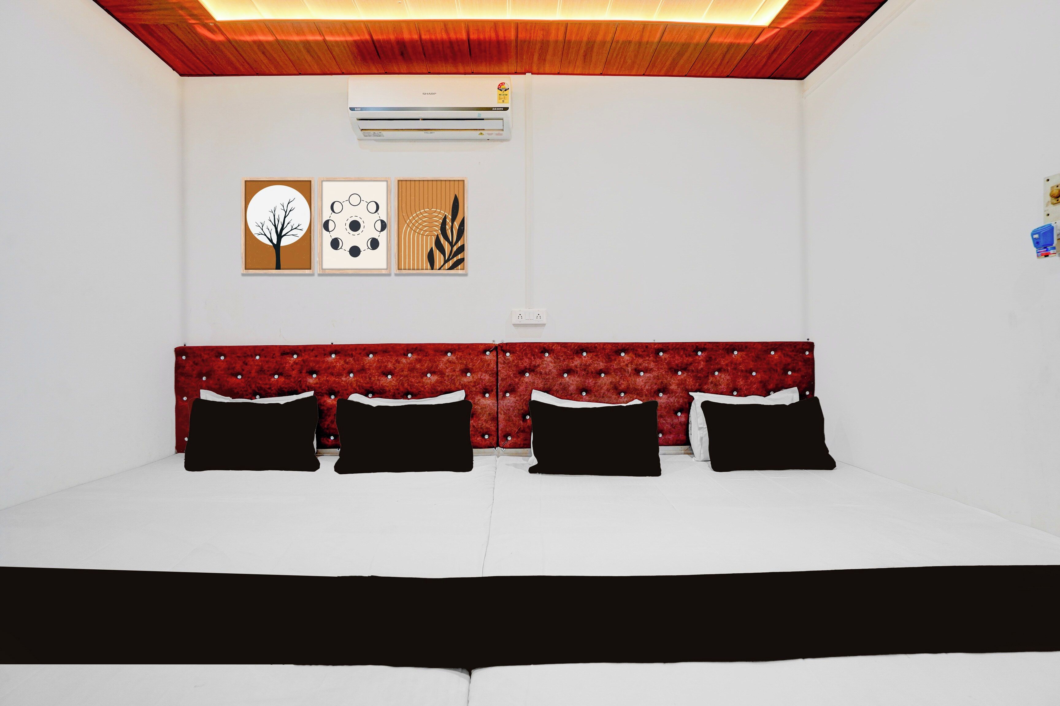 A room with a bed, a red upholstered headboard, and three black pillows.