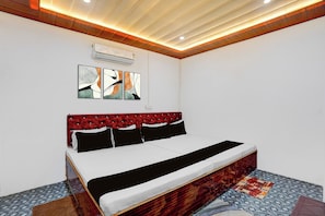 Une chambre à coucher comprenant un lit, une tête de lit, un climatiseur fixé au mur et des œuvres d’art abstraites accrochées au mur.