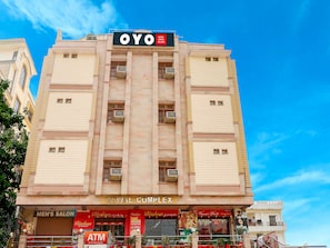 Un edificio de hotel con un letrero que dice 'OYO HOTEL Kewal Palace' y 'KEWAL COMPLEX' debajo.
