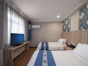 Quarto de hotel com duas camas, televisão, escrivaninha e ar condicionado.