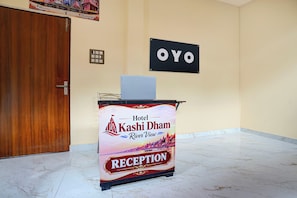A reception desk at Hotel Kashi Dam with a laptop on top, a sign for 'OYO' on the wall, and a marble floor. - Hotel O Kashi Dham River View (Varanasi)