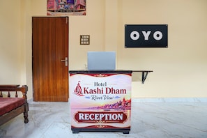 A reception desk at Hotel Kashi Dam with a sign indicating the location. - Hotel O Kashi Dham River View (Varanasi)