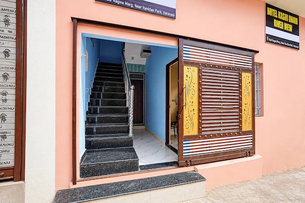 A hotel entrance with a staircase leading inside, a signboard above the entrance, and a decorative door with a metal grille. - Hotel O Kashi Dham River View (Varanasi)