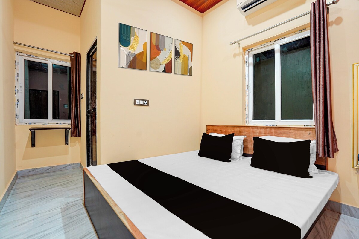 Ein Hotelzimmer mit Bett, einem Fenster mit Vorhängen, einer Wand-Klimaanlage und einer Steckdose.