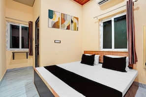 Ein Hotelzimmer mit Bett, einem Fenster mit Vorhängen, einer Wand-Klimaanlage und einer Steckdose.
