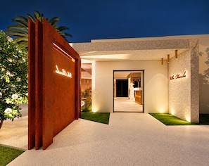 A modern hotel entrance with a red facade, a well-lit pathway, and a clear view into the interior. - Maison Blanche Rooms (San Leo)