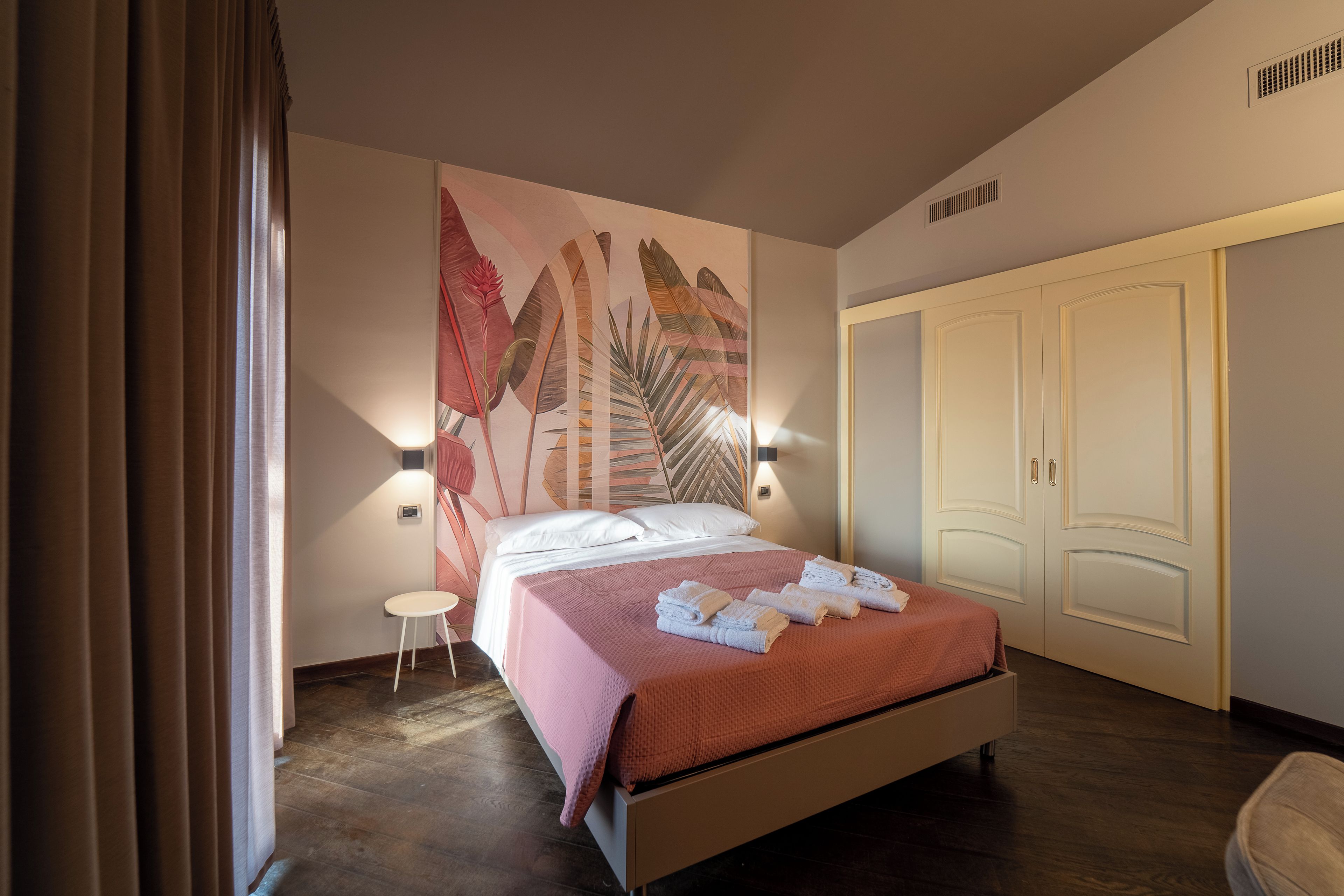 Una camera d'hotel con un letto, un comodino, una luce a parete e un armadio.