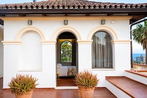 A building with a tiled roof, arched doorways, and a balcony with potted plants. - Maison Blanche Rooms (San Leo)