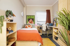 A compact bedroom with a bed, a desk, a chair, and a window with curtains. - Student Only William Murdoch (Birmingham)