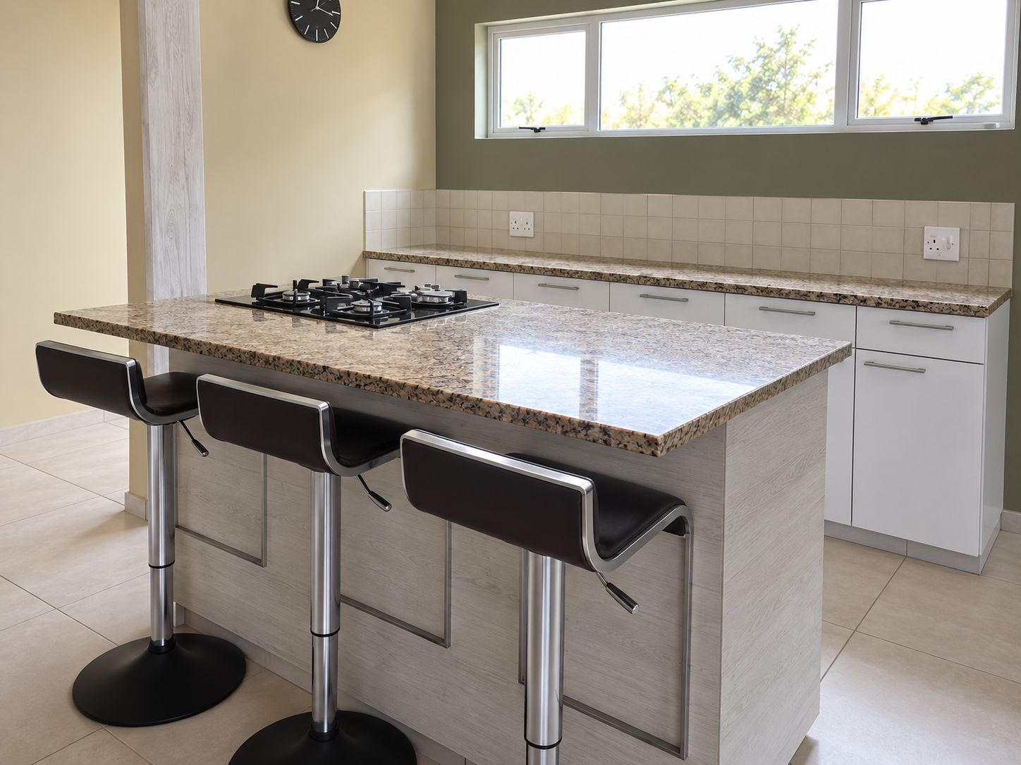 Una cocina con encimera de granito, taburetes de barra de acero inoxidable y una estufa a gas.