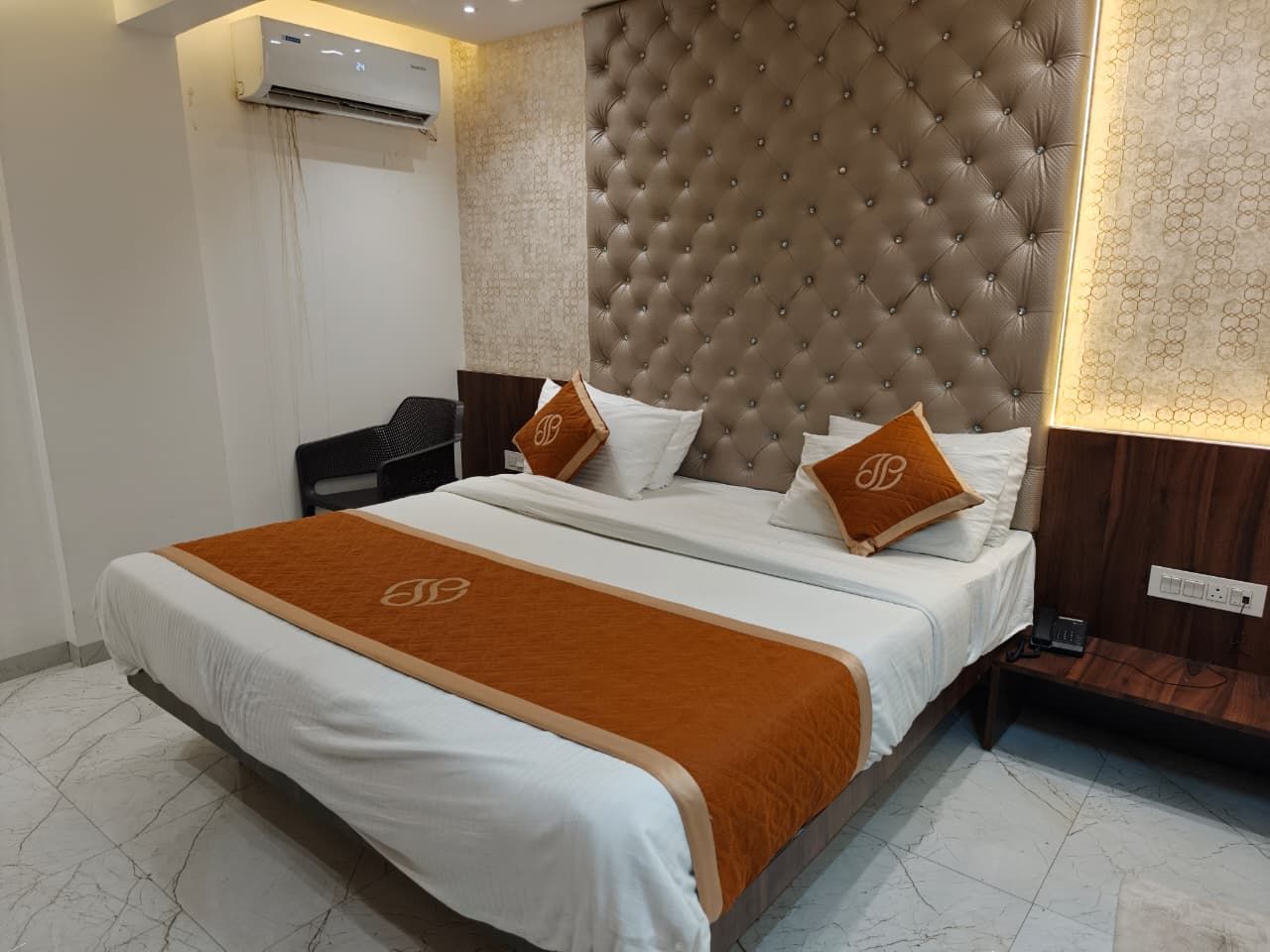 Une chambre d’hôtel avec un grand lit, une tête de lit, une table de chevet et un appareil de climatisation.