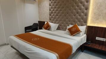 Une chambre d’hôtel avec un grand lit, une tête de lit, une table de chevet et un appareil de climatisation.