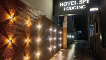 Un couloir avec une enseigne indiquant « Hotel Spy Lodging », agrémenté d’un motif géométrique sur le mur et d’un éclairage décoratif.