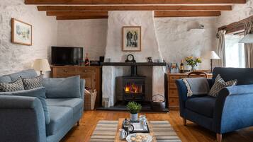 Una sala de estar acogedora con chimenea, sofás, una mesita de centro con pasteles y un televisor.