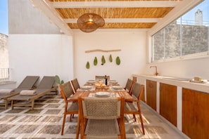 A dining area with a table set for four, surrounded by chairs, and a view of the cityscape through large windows. - Casa Cactus | Stylish Home with Private Rooftop Terrace (Carovigno)