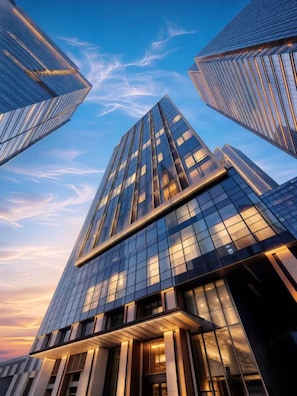 Un moderno edificio de gran altura con fachada de vidrio y entradas iluminadas.