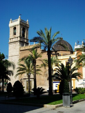 A historic building with a bell tower and dome, surrounded by palm trees and a street lamp. - Mon Suites Marina (Valencia)