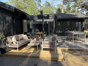 Eine Terrasse im Freien mit Holzdeck, einer Couch, einem Tisch und Stühlen.