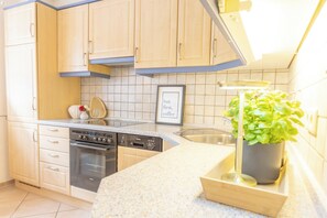 A kitchen with light wooden cabinets, a stainless steel sink, a dishwasher, and a stove. - Your spacious vacation home, Anita, in St. (Sankt Peter-Ording)
