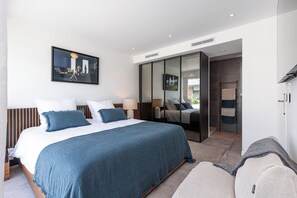 Une chambre d’hôtel moderne dotée d’un grand lit, d’une armoire, d’un coin salon et offrant une vue sur l’extérieur.