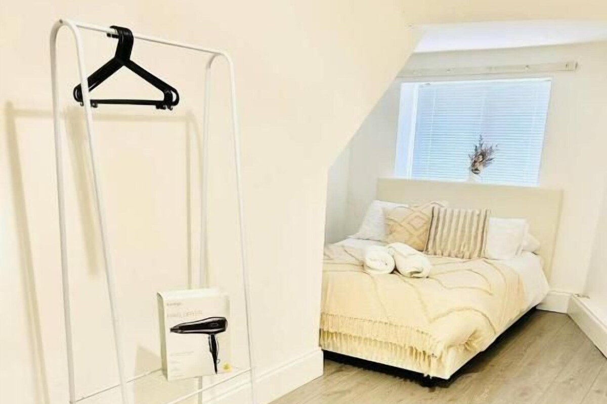 Ein Schlafzimmer mit einem Bett, einem weißen Kleiderschrank und einem Fenster mit Jalousien.