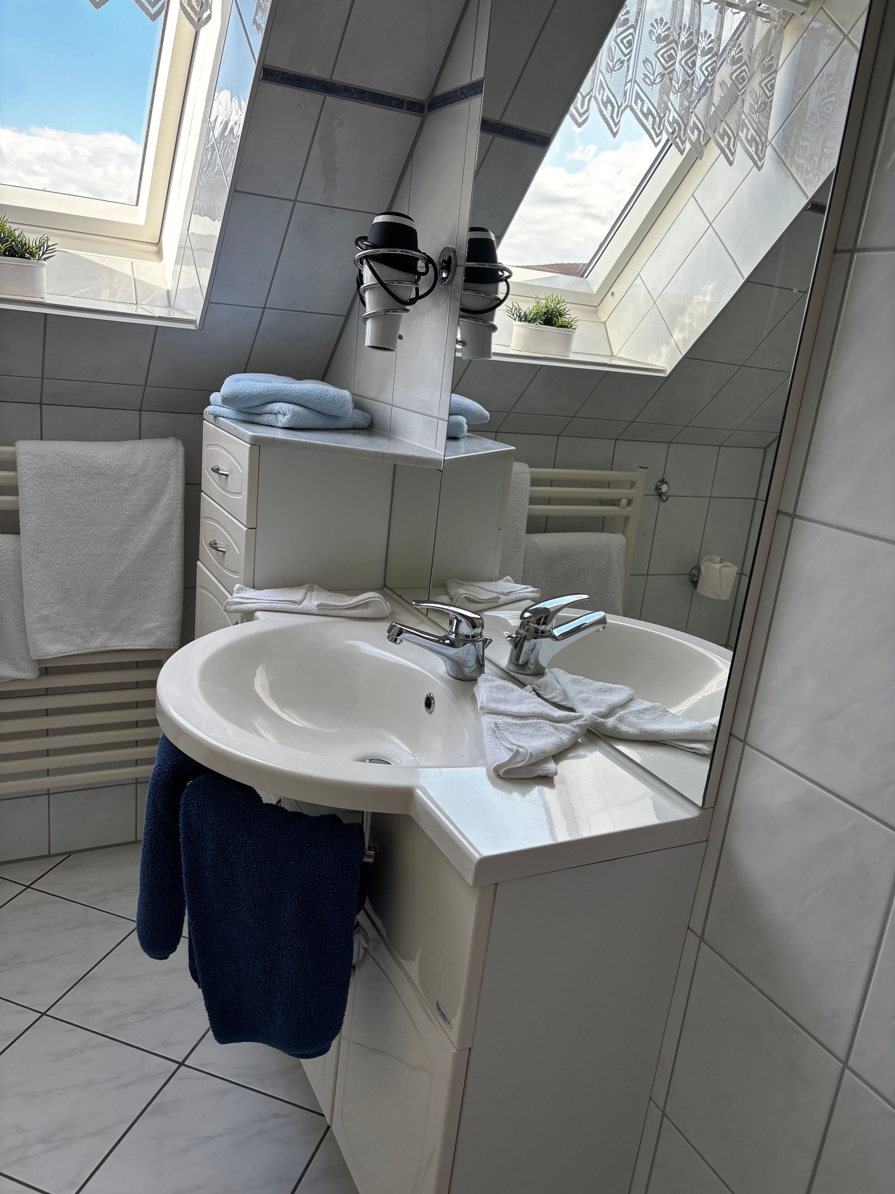 A modern bathroom with a skylight, a white sink, and a mirror.
