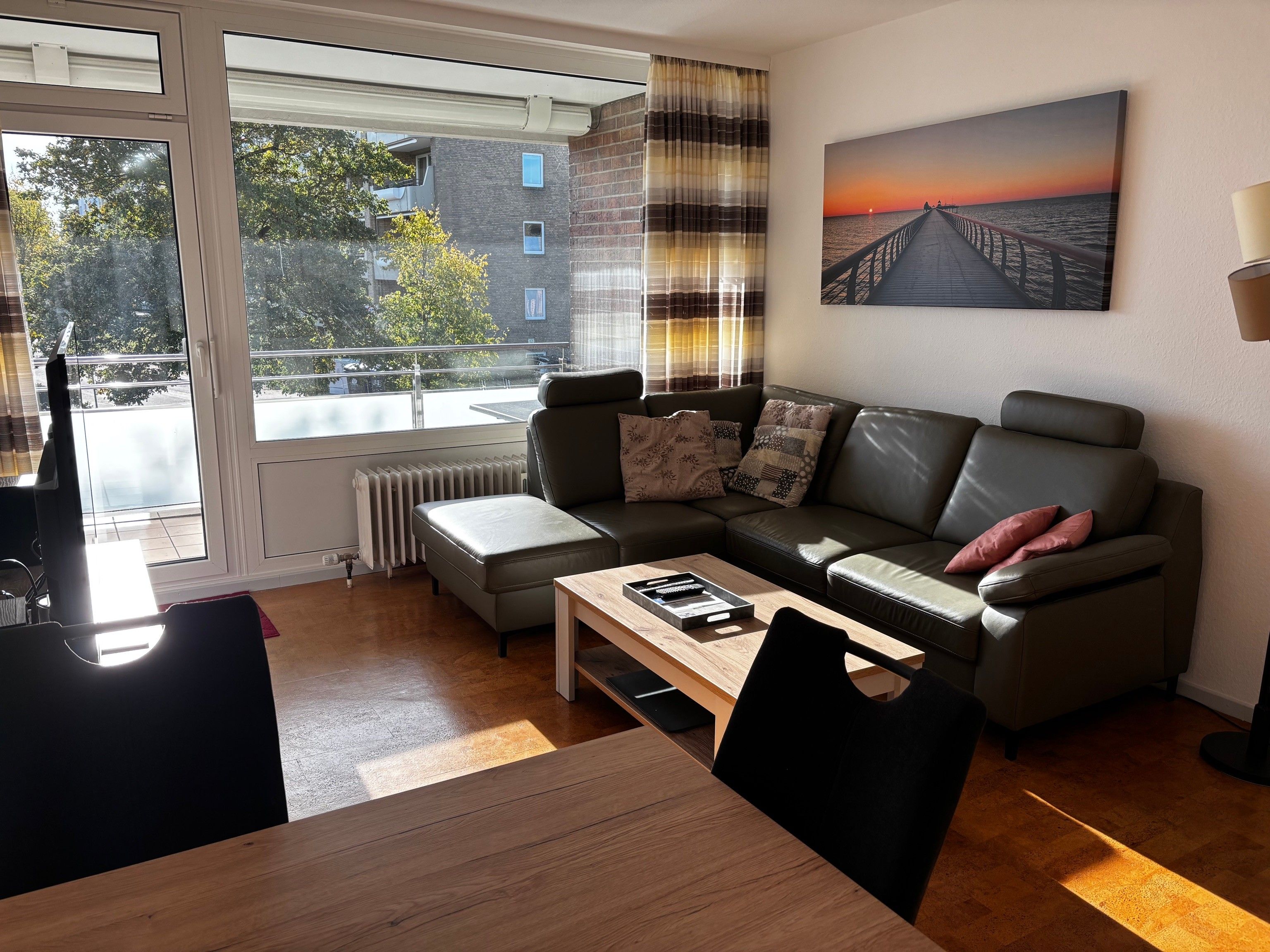 A modern living room with a sofa, a coffee table, and a view of a building through a window.