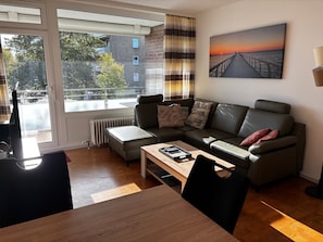 Una sala de estar moderna con un sofá, una mesa de centro y vistas de un edificio a través de una ventana.