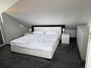 A bedroom with a bed, bedside tables, a lamp, and a wardrobe.