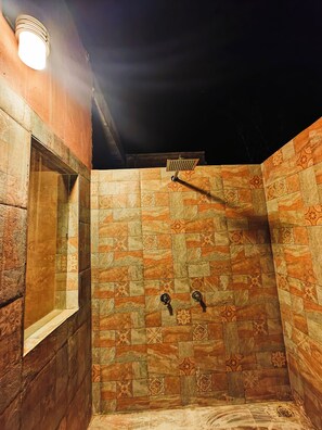 Un área de ducha con paredes de azulejos y una ventana.