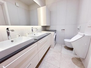 Ein modernes Badezimmer mit einem großen Waschbecken, einer Toilette und einem Spiegel.