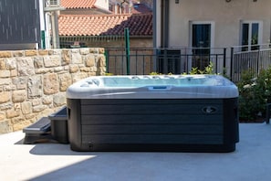 Ein Whirlpool in einer Außenanlage mit einer Steinmauer und einem Metallzaun im Hintergrund.