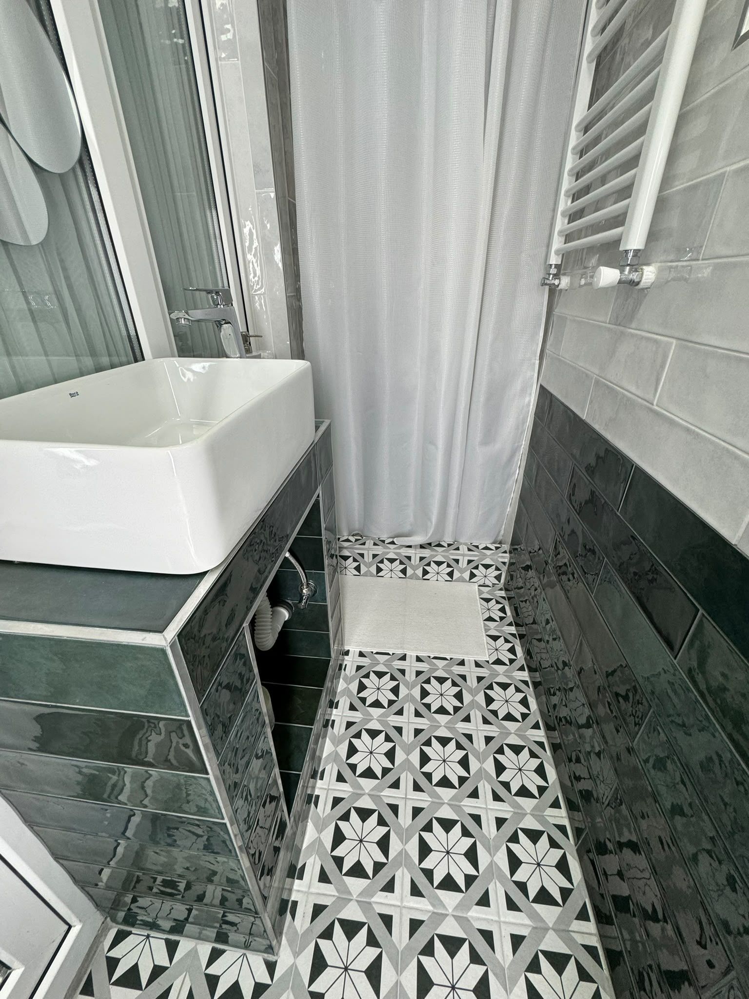 Un baño con bañera, cortina de ducha y azulejos estampados.