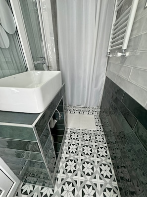 Un baño con bañera, cortina de ducha y azulejos estampados.