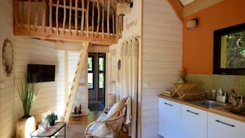 A cozy interior with a wooden staircase, a dining area, and a kitchen with white cabinets.