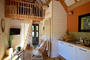 A cozy interior with a wooden staircase, a dining area, and a kitchen with white cabinets. - Lodge Mont Ventoux - Cabanes de Provence (Lafare)
