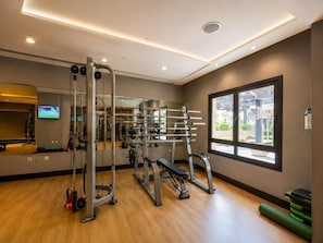 Un gimnasio con equipo de ejercicio, un televisor y una ventana con vistas.