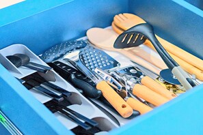 Un tiroir contenant divers ustensiles de cuisine, notamment des couteaux, une râpe et une spatule.