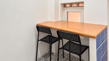 Una pequeña cocina con mostrador, dos sillas, un ventanal y baldosas de suelo estampadas.