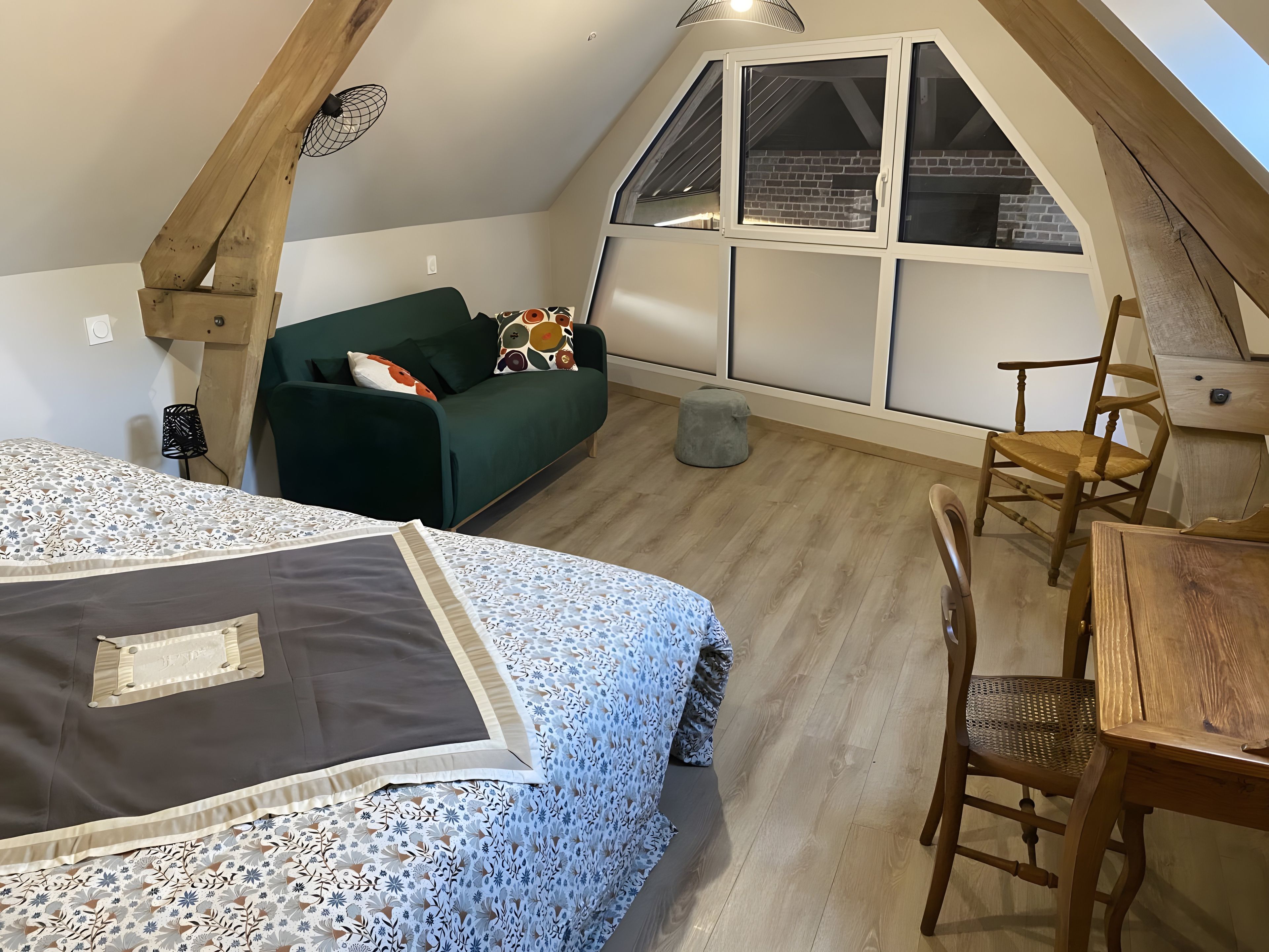 Une pièce de style loft comprenant un lit, un canapé vert, une table à manger et une chaise en bois.