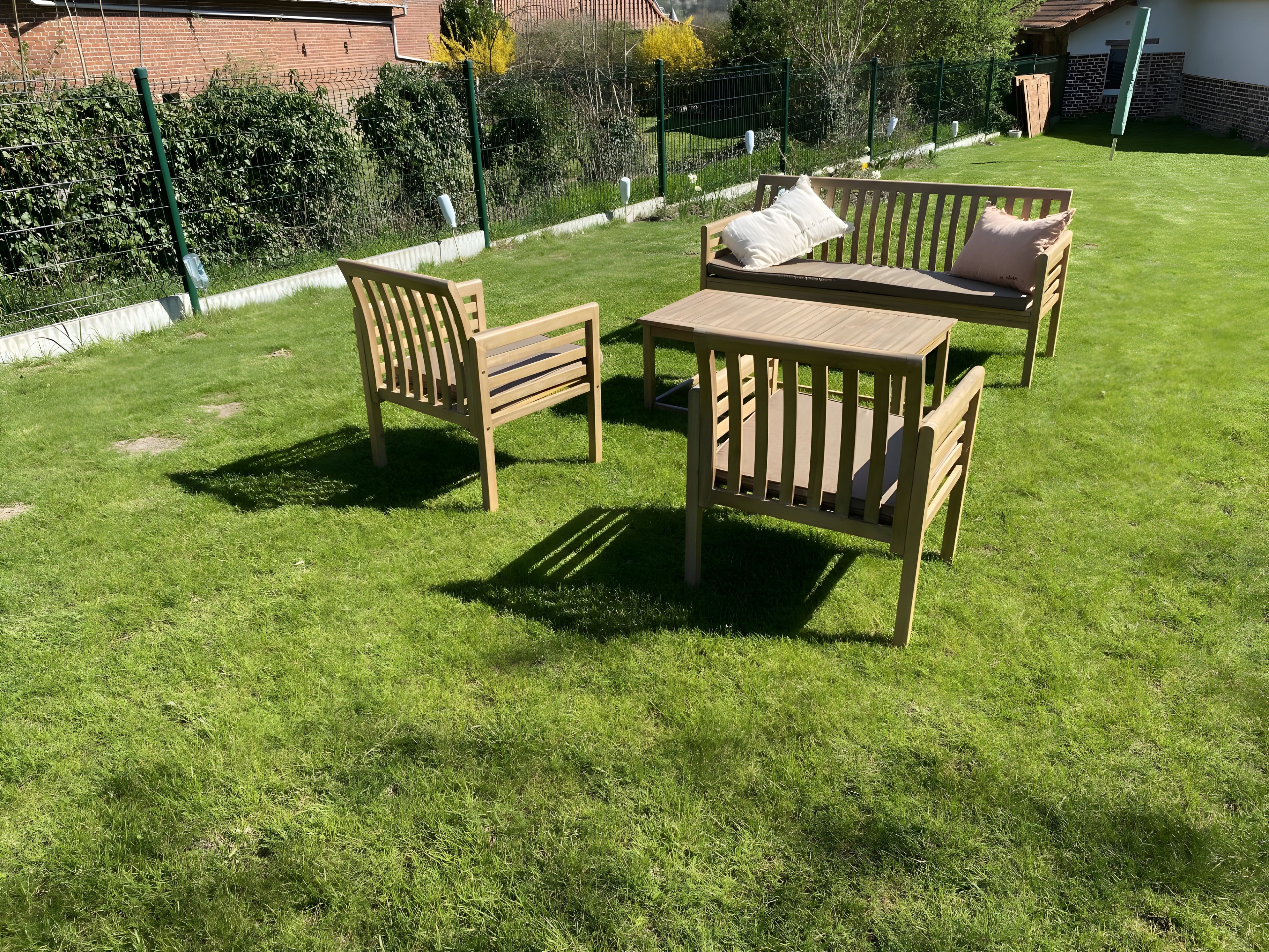 Un espace patio avec une table en bois et deux chaises, entouré d’une pelouse bien entretenue.