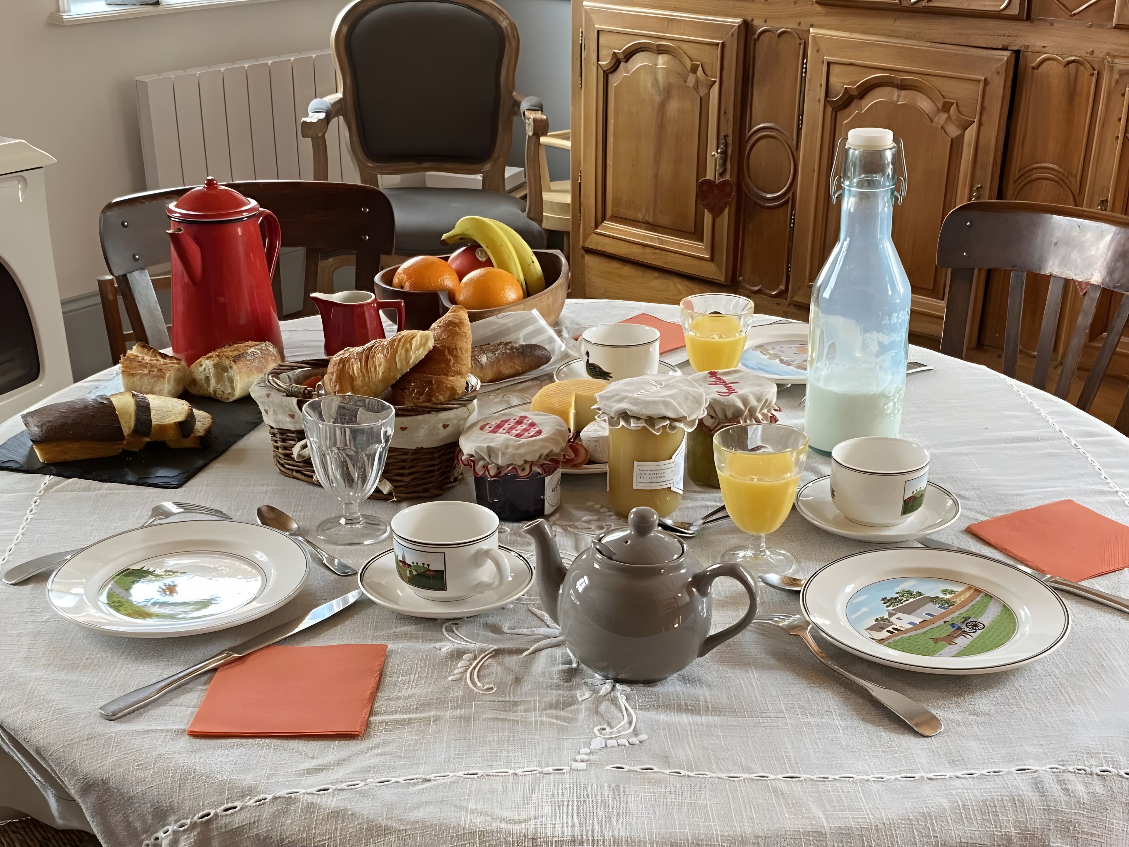 Une table de petit-déjeuner dressée avec divers aliments, notamment du pain, des fruits et des boissons.