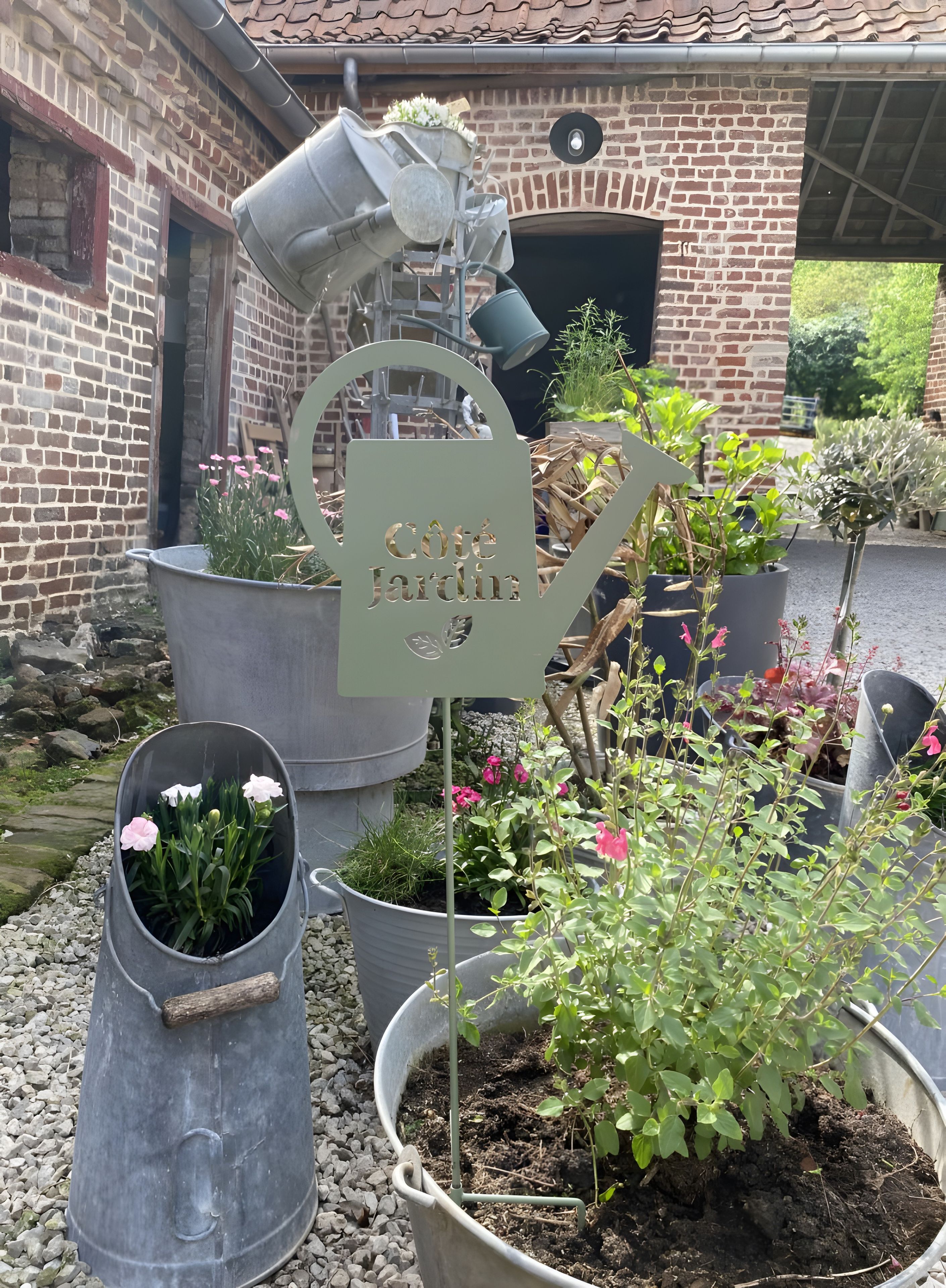 Un espace jardin agrémenté de plantes en pot et d’un panneau indiquant un point d’eau.