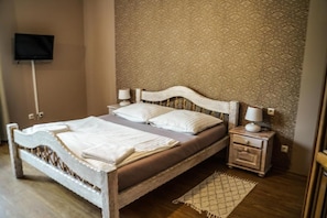 Ein Schlafzimmer mit einem Bett, Nachttischen, einem Fernseher und einer Wand mit Muster.
