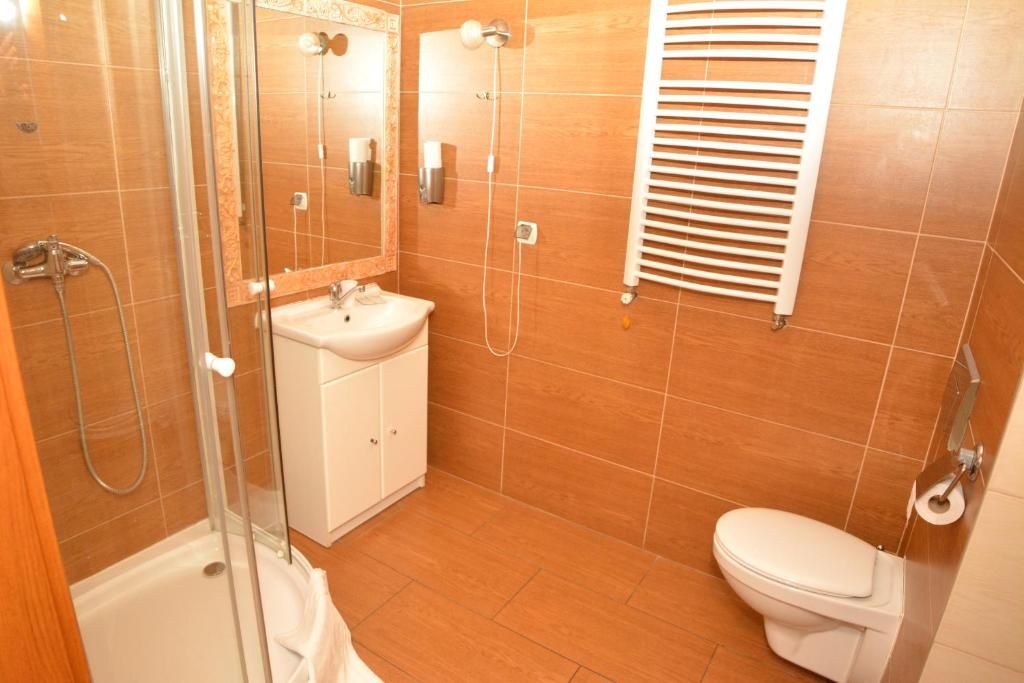 Ein Badezimmer mit Duschkabine aus Glas, einem weißen Waschbecken und einer Toilette.