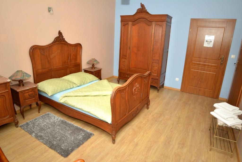 Ein Schlafzimmer mit einem hölzernen Bett, einem Kleiderschrank, einer Tür und einem kleinen Tisch mit einer Lampe.