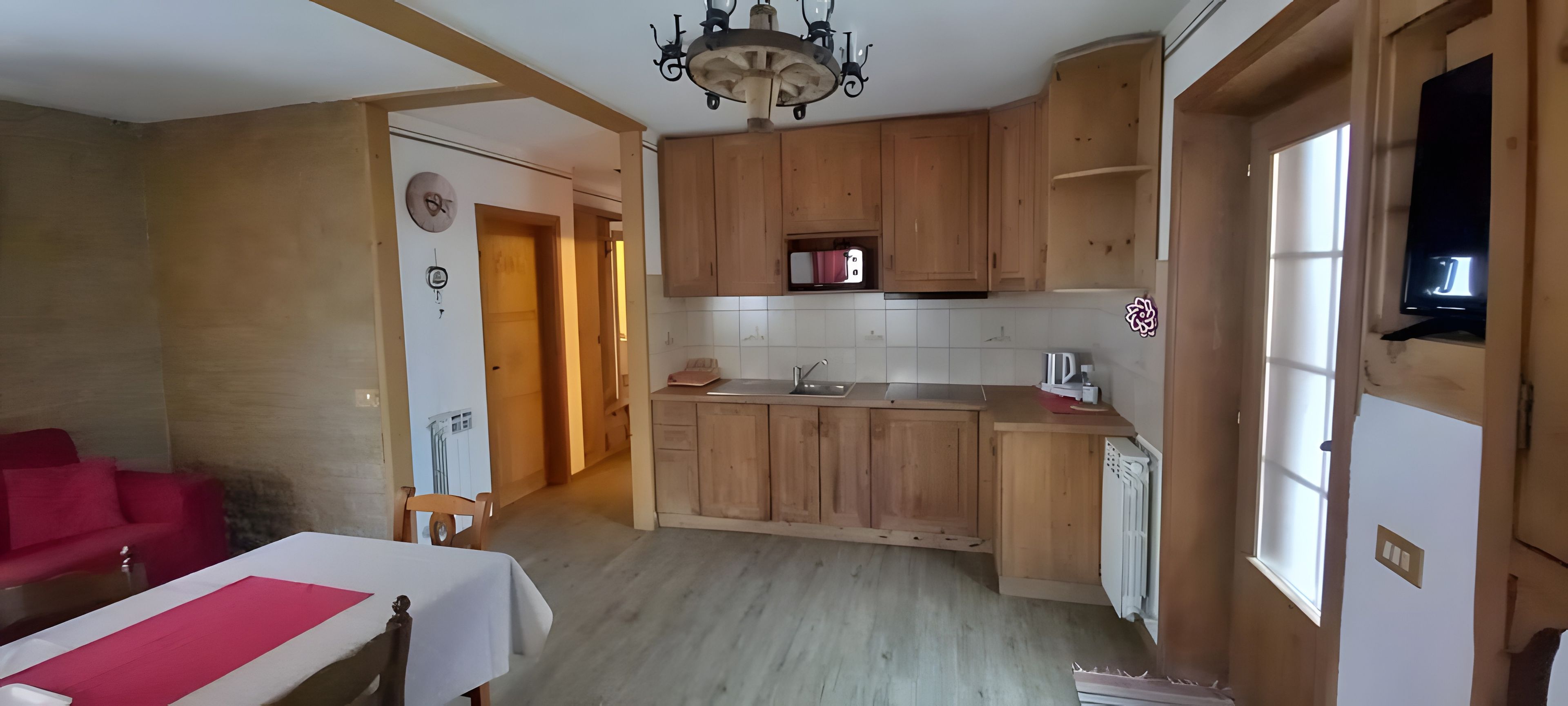 Une cuisine avec des meubles en bois, un four à micro-ondes encastré et une fenêtre.