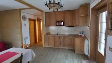 Une cuisine avec des meubles en bois, un four à micro-ondes encastré et une fenêtre.