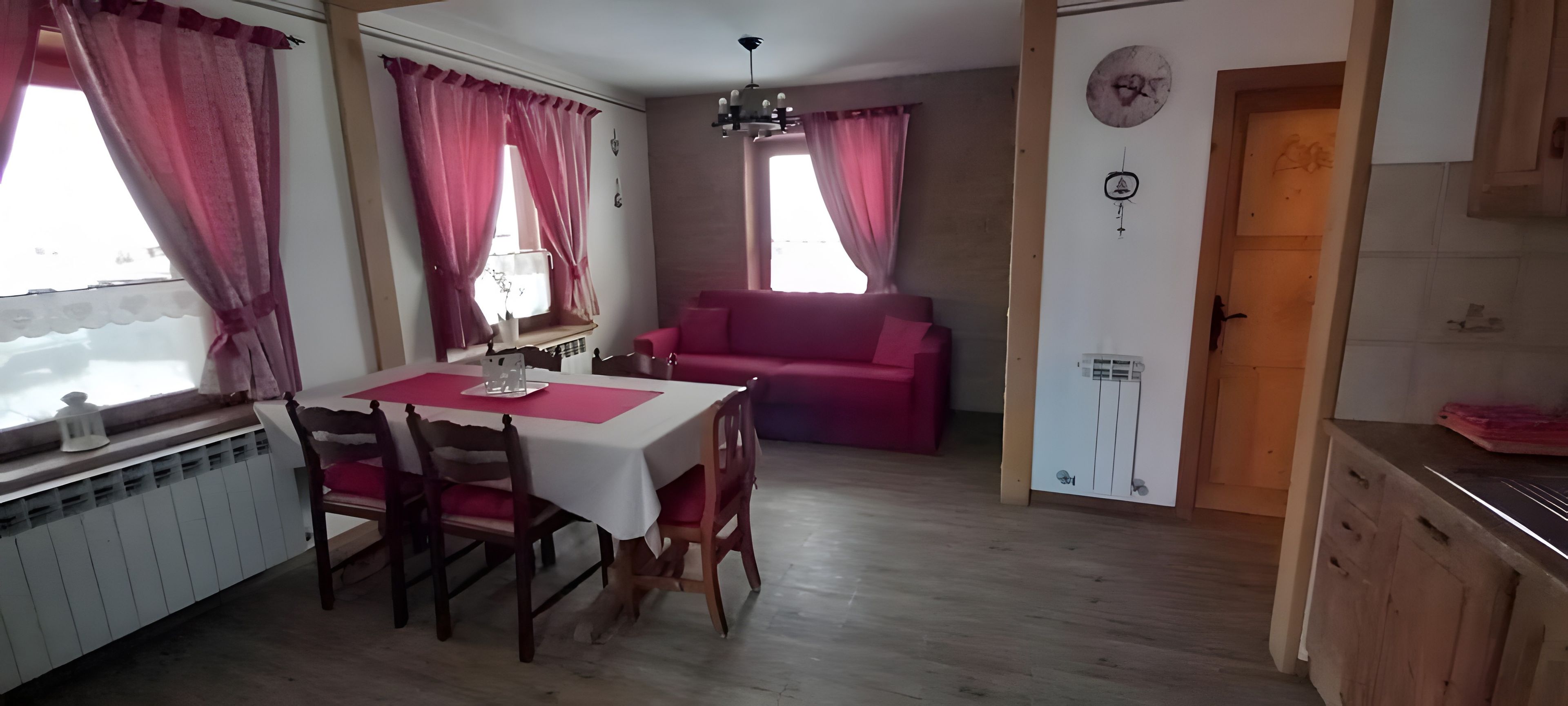 Un coin repas avec une table et des chaises, un canapé et une fenêtre avec des rideaux.