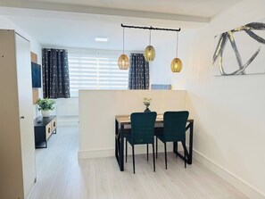 Een moderne eetruimte met een houten tafel en twee stoelen, een kleine plant op de tafel en een hanglamp.